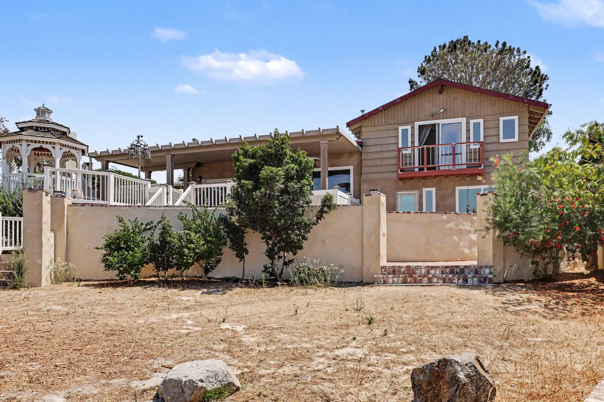The gazebo and residence standing above graded ground and boulders.