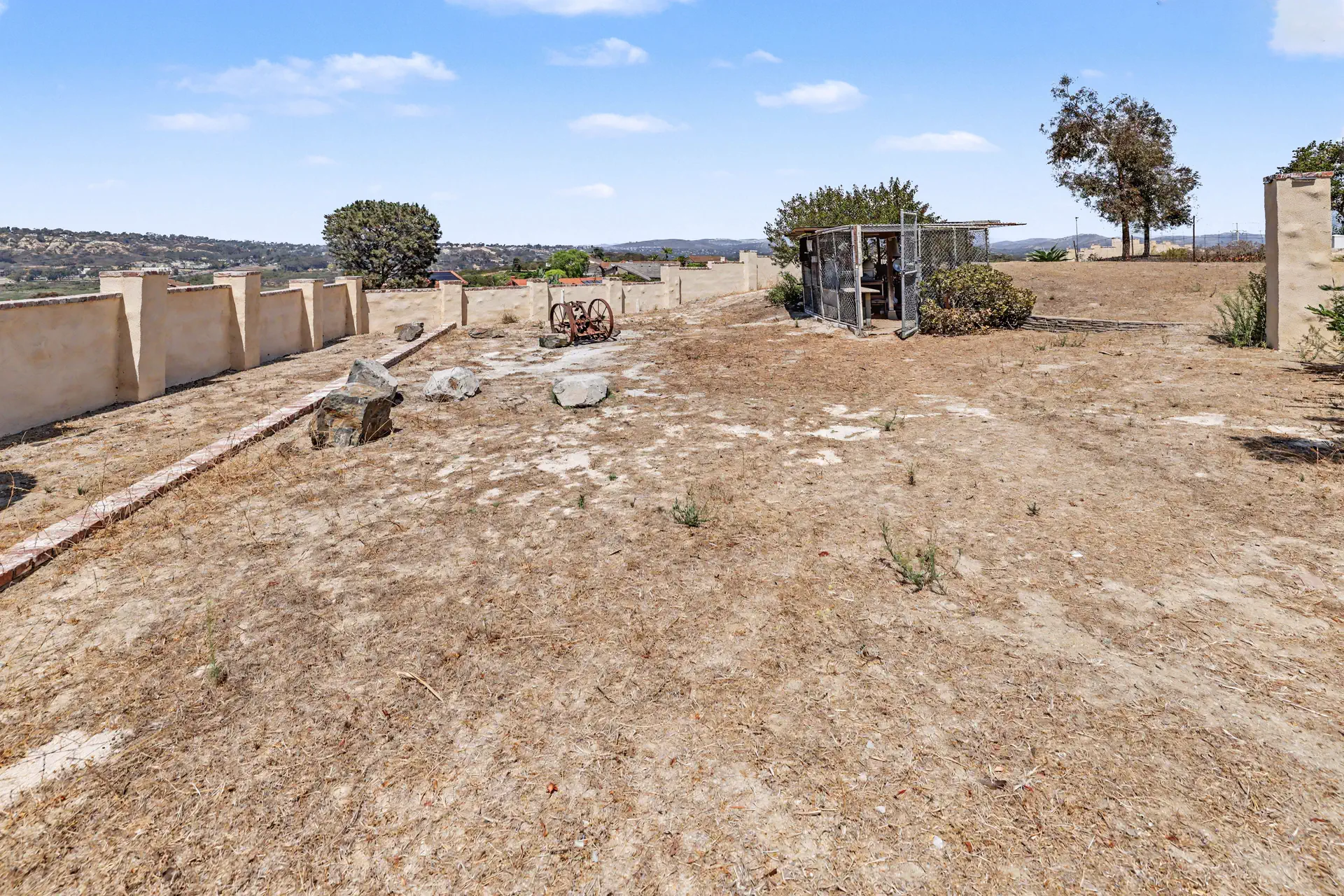Cleared level ground running to a low boundary wall at the eastern edge of the parcel.