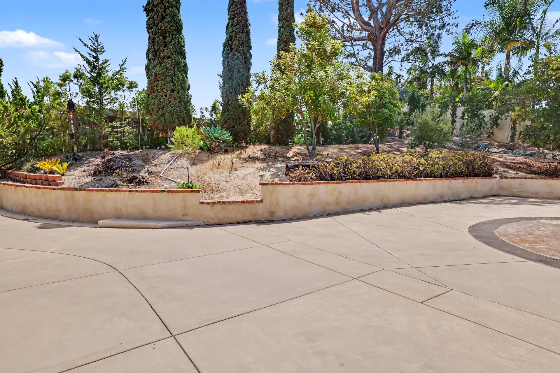 Terraced planters and columnar cypress along the boundary of the parcel.